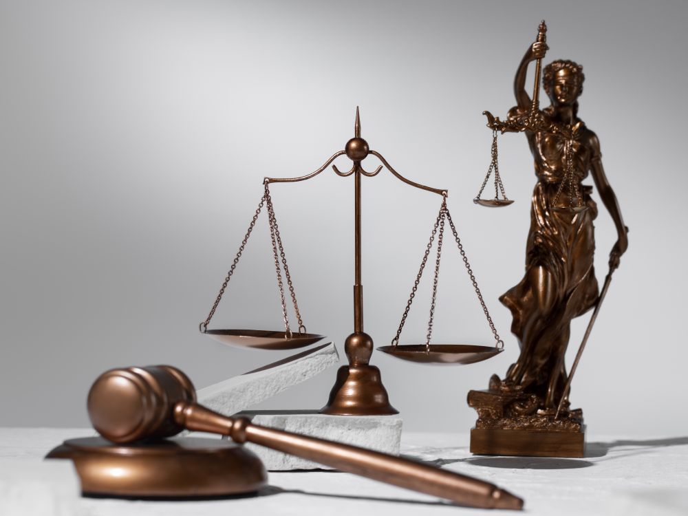 Balanza de la justicia y un mazo de juez, símbolos del Derecho Penal y la defensa en un juicio.